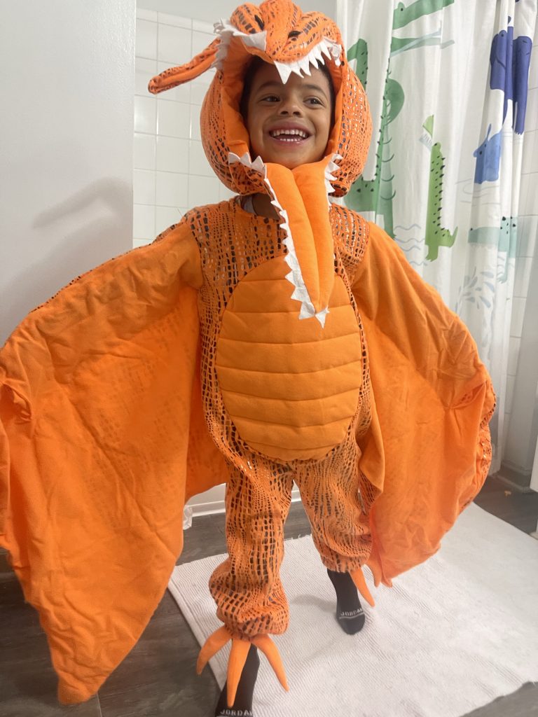 Child, boy around the age of 5 wearing a dinosaur costume from Pottery Barn Kids.